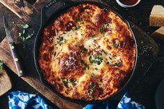 a pizza with cheese and sauce in a pan on a cutting board next to some slices of bread