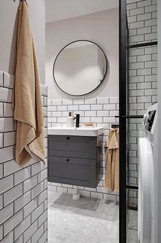 A modern bathroom with white subway tiles with black grout and a subtle white marble hexagon floor tile