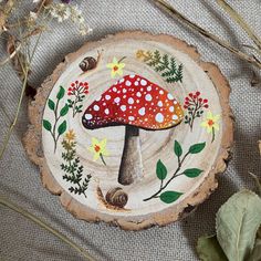 a red mushroom sitting on top of a tree stump next to leaves and flowers in the background