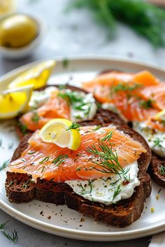 there is a plate with bread and salmon on it, along with lemon wedges