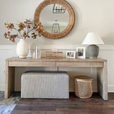 a table with a mirror, lamp and vase on it in front of a white wall