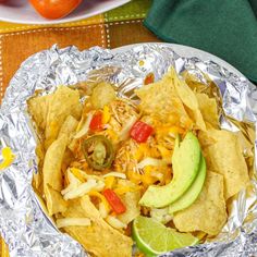 an aluminum foil plate topped with nachos and cheese