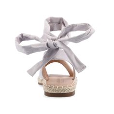 Introducing the Emelie wrap-around sandal by Journee Collection—a stylish fusion of comfort and sophistication. This open-toe sandal features a distinctive wrap-around ankle strap with whipstitch trim and espadrille details, creating a trendy look. Designed for all-day wear, the Emelie sandal comes equipped with a 4 mm Tru Comfort Foam™ Footbed for a cushioned feel, and its flat sole ensures both ease of movement and a laid-back charm. Crafted with faux suede uppers, it exudes a luxurious appear Adjustable Cross-tied Round Toe Sandals, Spring Ankle Wrap Sandals With Adjustable Fit, Spring Sandals With Ankle Strap And Cross-tied Detail, Spring Beach Lace-up Sandals With Closed Toe, Spring Cross-tied Ankle Strap Sandals, Spring Vacation Closed Toe Lace-up Sandals, Spring Sandals With Wrapped Flat Heel, Spring Vacation Lace-up Closed Toe Sandals, Spring Adjustable Cross-tied Sandals