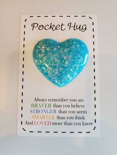 a blue heart shaped brooch sitting on top of a piece of paper with the words pocket hug