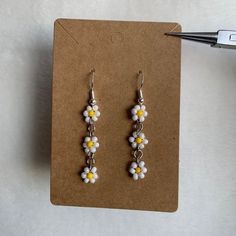 a pair of earrings with yellow and white flowers hanging from it's earwires