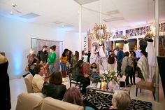 a group of people standing around in a room with lights on the ceiling and chandeliers hanging from the ceiling