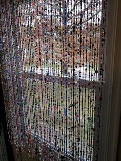 a window with beads hanging from it's side and a tree in the background