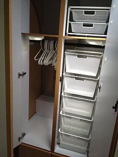 an open closet with several drawers and white baskets on the bottom shelf in front of it