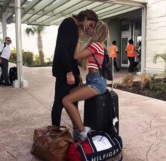 a man and woman kissing while standing next to luggage