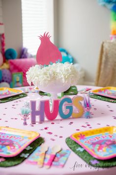 the table is decorated with pink and green plates, napkins, and paper flowers