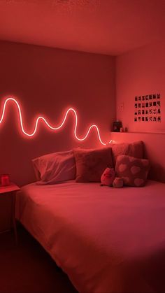 a bed in a room with red light coming from the headboard and pillows on it