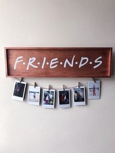 a wooden sign that says friends hanging on a wall with photos pinned to it's sides