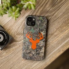 a phone case with an image of a deer head on it and some plants next to it