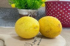 two lemons sitting on top of a cutting board next to a potted plant