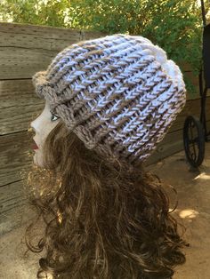 a mannequin head wearing a gray and white knitted hat with long hair