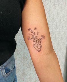 a woman's arm with a heart and flowers tattoo on the left inner arm