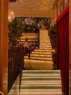 a man sitting on top of a set of stairs in front of a red curtain