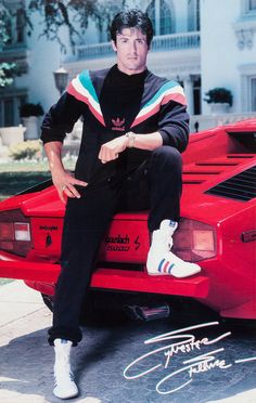 a man sitting on top of a red sports car