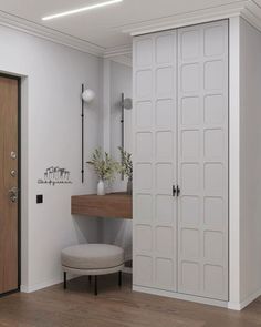 an empty room with white walls and wooden flooring has a round ottoman in front of the door