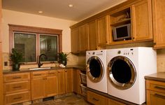 a washer and dryer in a kitchen with wooden cabinets