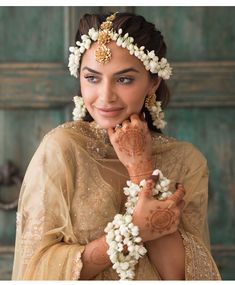 a woman with henna on her face and hands holding flowers in front of her face