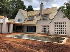 a house being built in the middle of a field with dirt and trees around it