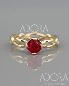 a gold ring with a red stone in the center and two twisted bands around it