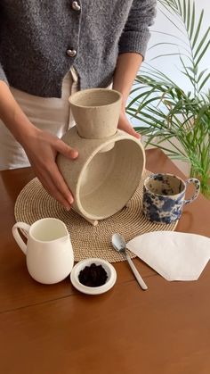 a woman is pouring coffee into a cup on top of a table with other items