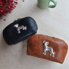 two purses sitting on top of a table next to a cup