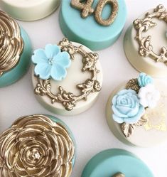 there are many decorated cupcakes with gold and blue frosting on the top