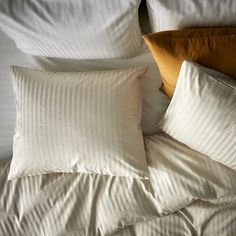 an unmade bed with white sheets and pillows