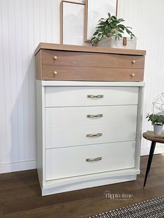 a white dresser with three drawers next to a potted plant on top of it