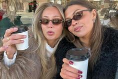 two women taking a selfie while holding coffee cups