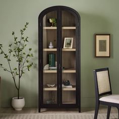 a room with a chair, table and bookshelf on the floor in front of a green wall