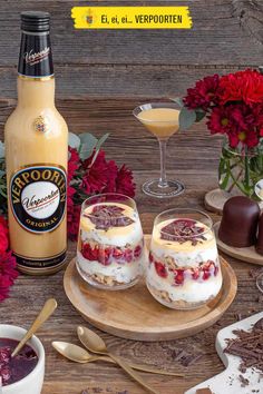 two desserts on wooden plates next to flowers and bottles of boojura sauce