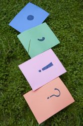 four pieces of paper with faces on them laying in the grass, one has a smiley face