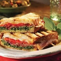 two sandwiches are stacked on top of each other, with basil sprigs in the background