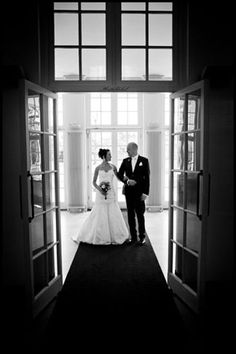 a bride and groom standing in an open doorway at the end of their wedding day