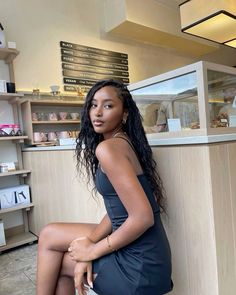 a woman sitting on top of a counter next to a white bag in a store