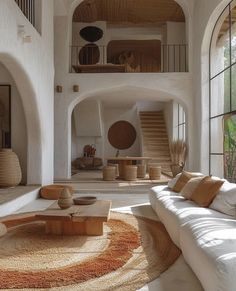 a living room filled with white furniture and lots of natural wood accents on the walls