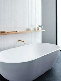 a white bath tub sitting in a bathroom next to a wall mounted shelf with candles on it