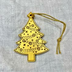 an ornament shaped like a christmas tree on a white cloth with gold thread