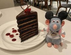 a mouse figurine next to a piece of cake on a plate at a restaurant