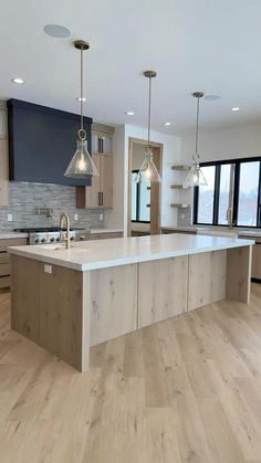 a large kitchen with an island in the middle and two pendant lights hanging from the ceiling