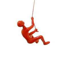 a red plastic figure hanging from a string on a white background with a person in the air