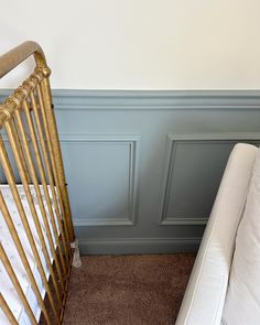 a crib next to a white bed in a room with blue walls and brown carpet