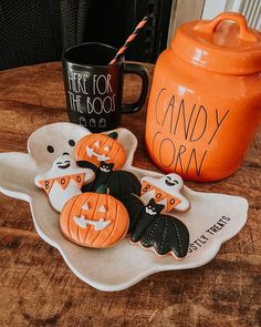 there are three decorated cookies on a plate next to a coffee mug and an orange canister