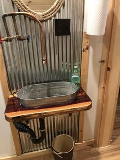 a metal sink sitting on top of a wooden table next to a wall mounted faucet