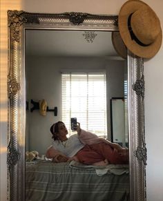 a person taking a selfie in a mirror with a hat on top of it