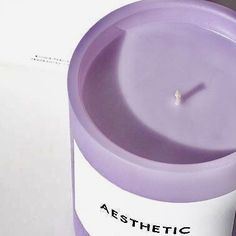 a purple candle sitting on top of a white table next to a box with the word aesthetic written on it